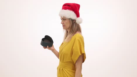 woman in santa hat looks disappointed with empty heart-shaped gift box
