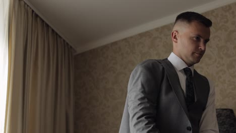 Handsome-groom-businessman-wearing-gray-jacket-at-home-in-living-room,-white-shirt-with-black-tie