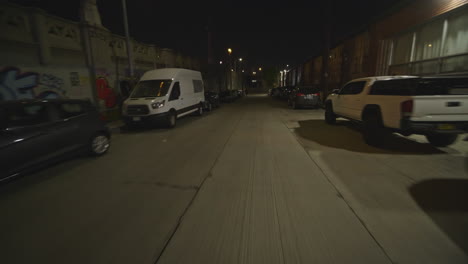 fpv shot down an alleyway at nighttime with police lights reflecting