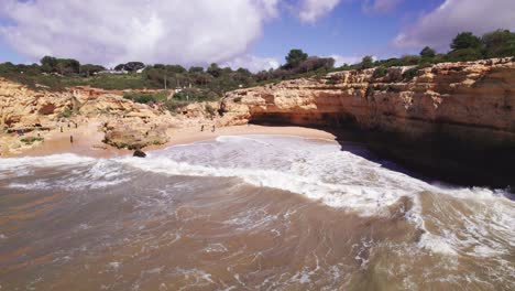 Coastline-view-with-beach-cove-and-crashing-waves-by-aerial-4k-drone-at-Albandeira-beach-in-the-Algarve-region-of-Portugal