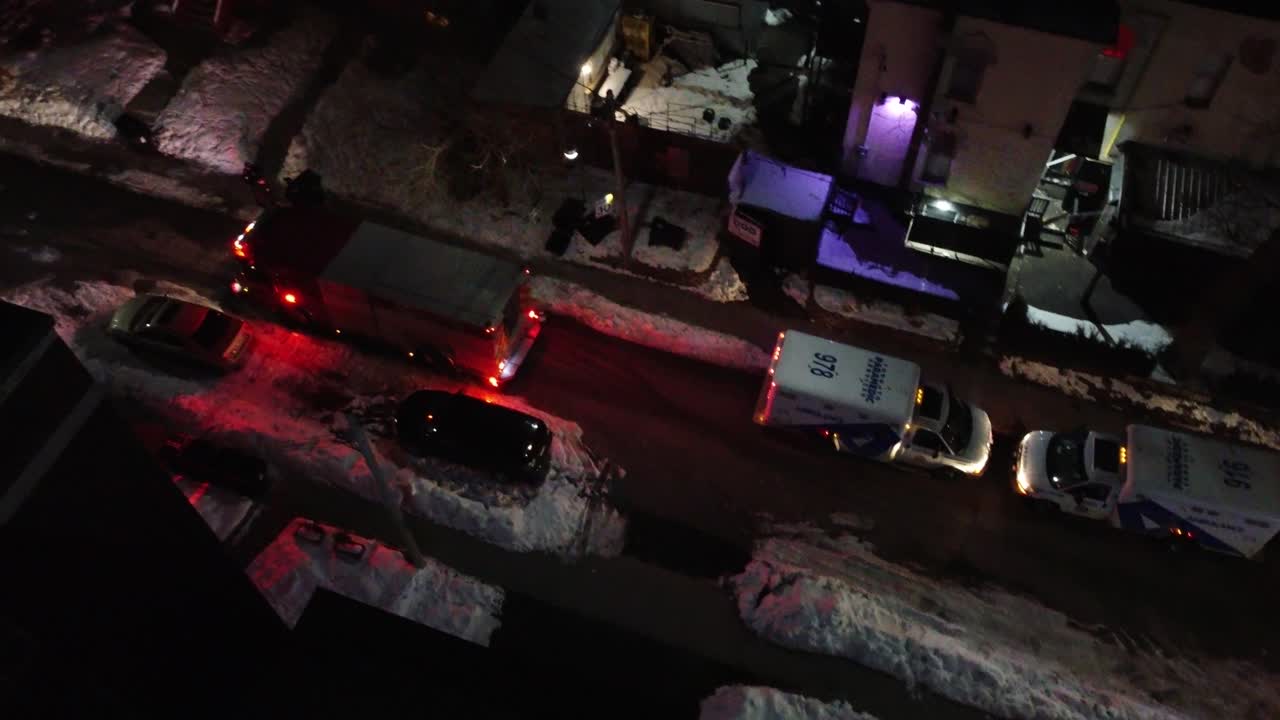 Emergency medical services approach snowy house lights on at night