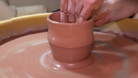 shaping up a the walls of a pottery cup on the wheel