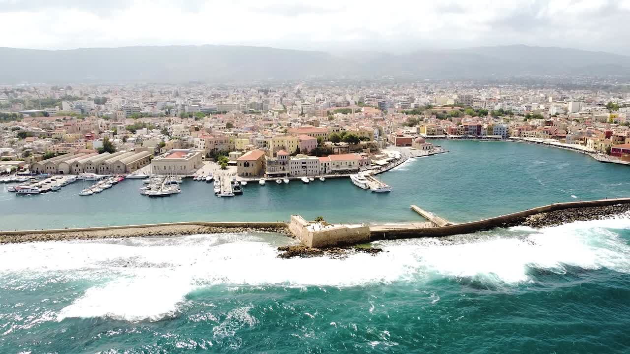 Foamy waves hitting lighthouse of Chania, aerial drone view