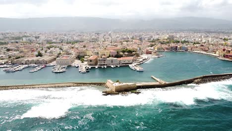 Foamy-waves-hitting-lighthouse-of-Chania,-aerial-drone-view