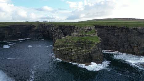 majestic kilkee cliffs on a cloudy day, waves crashing against the rugged coastline, aerial view