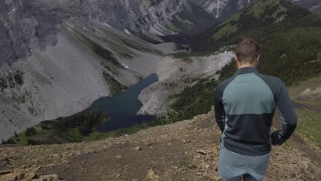 Hiker-on-mountain-ridge-taking-photos-walking-downhill-Rockies-Kananaskis-Alberta-Canada