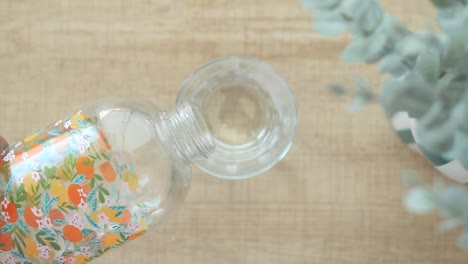 pouring water from a citrus patterned bottle into a clear glass