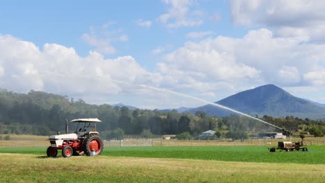 tractor irrigating field with mountain backdrop