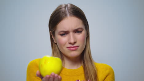 Porträt-Einer-Nachdenklichen-Frau,-Die-Auf-Grauem-Hintergrund-Zwischen-Apfel-Oder-Kuchen-Wählt.