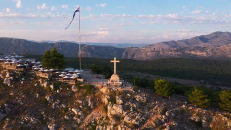 aerial view of mountain srd and cross in dubrovnik, croatia during sunset in 4k reveal shot flying backwards