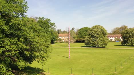 Flying out from a Maypole on a village green on a summer day