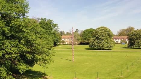 flying out from a maypole on a village green on a summer day