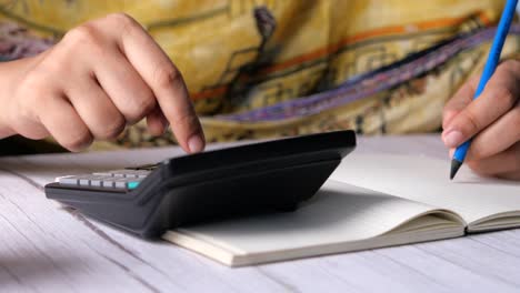 person calculating on a calculator and notebook