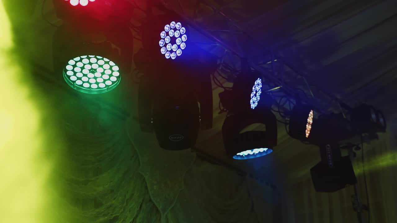 Colored spotlights in the nightclub. Spotlights above the stage. Lasers of a farm spinning and shimmering brightly.