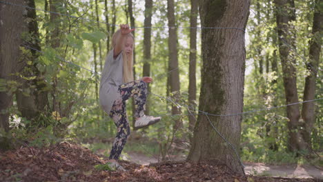 a girl in a summer camp hike overcomes an obstacle by crawling on the ground and tumbling. fun children's challenges