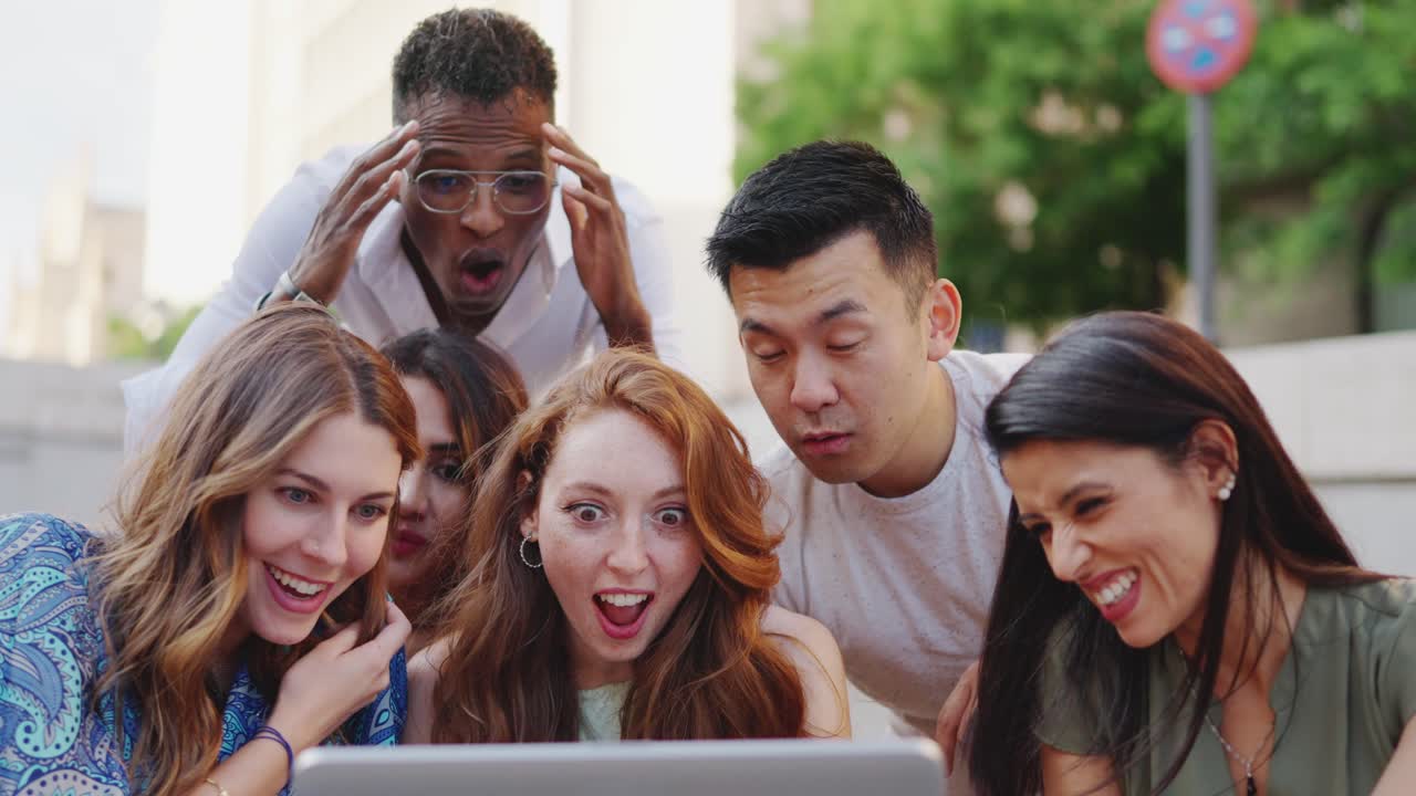 Diverse Group of Friends Reacting with Shock and Amusement to Content on a Laptop Outdoors