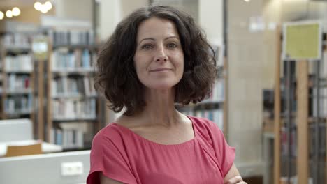 mujer caucásica sonriente posando en la biblioteca pública