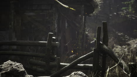 old rustic fence and abandoned cottage in a forest during the twilight hours