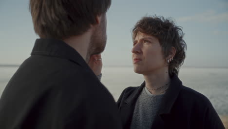 woman gently touching face of her boyfriend outdoors by frozen lake