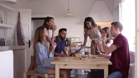 amigos adultos jóvenes bebiendo y comiendo bocadillos en la cocina, filmado en r3d