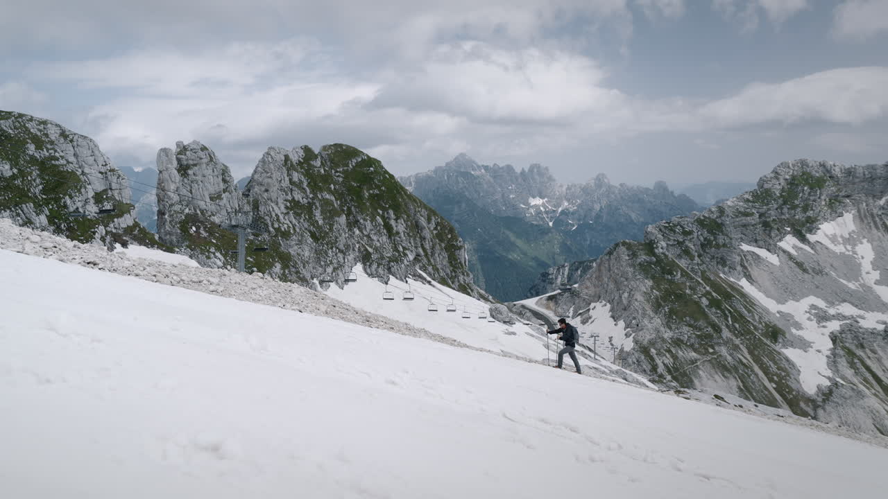 Hiker climbing up a hill on mountain Kanin next to skiing slopes
