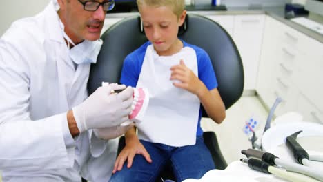 Dentist-showing-model-teeth-to-patient