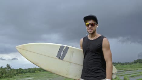 skateboarder traveling with surfboard in tropics