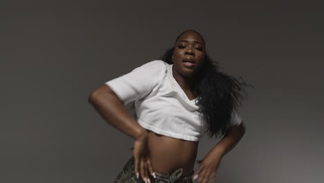 studio portrait shot of young woman dancing with low key lighting against grey background 5