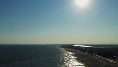 slow high up pull away over the ocean at long beach, new york, glistening sunset - shore on the right side of the scene