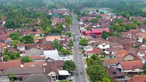 buildings and trafficked road in mungkid in indonesia, forward aerial