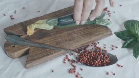 still life ingredients for a gourmet recipe: a hand reaches in and places two courgettes on a wooden axe