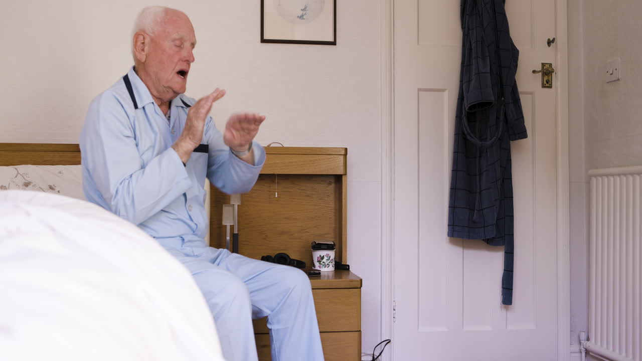 Elderly man sitting on a bed looking sad