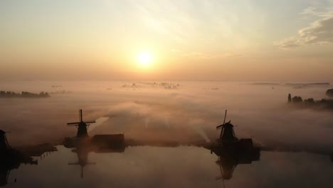 El-Dron-Vuela-Lejos-De-Los-Molinos-De-Viento-De-Zaanse-Schans-Durante-El-Amanecer-Con-Mucha-Niebla-Y-Las-Siluetas-De-Los-Molinos-De-Viento-En-Las-Imágenes-Aéreas-De-Los-Países-Bajos-4k