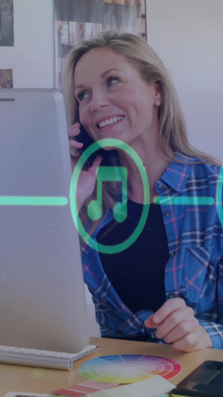 Animación de un diagrama de flujo de iconos sobre una mujer caucásica levantando el teléfono móvil mientras trabaja en un ordenador de escritorio.