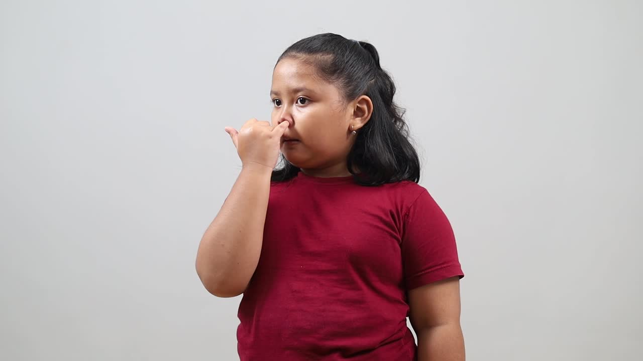 Simpatica bambina asiatica che si fruga il naso con il dito