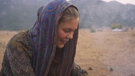 mujer joven en el campamento preparando comida por fogata, humo y conos quemados, cámara lenta, campamento salvaje, estilo de vida nómada al aire libre