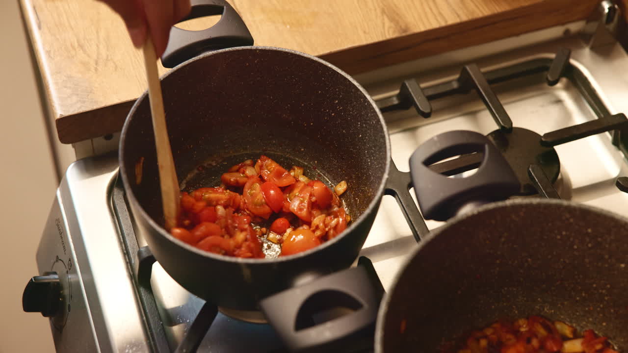 una mujer cocinando una salsa de tomate en una olla en la estufa