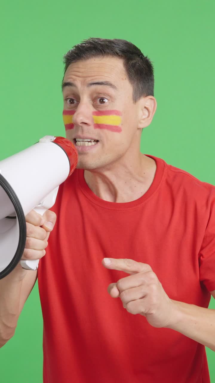 Excited man with spanish flag on face using a megaphone