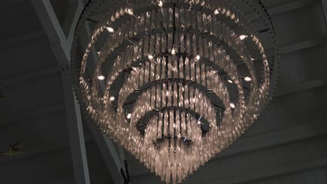 Slow-orbiting-shot-around-a-luxury-crystal-chandelier-hanging-from-a-ceiling