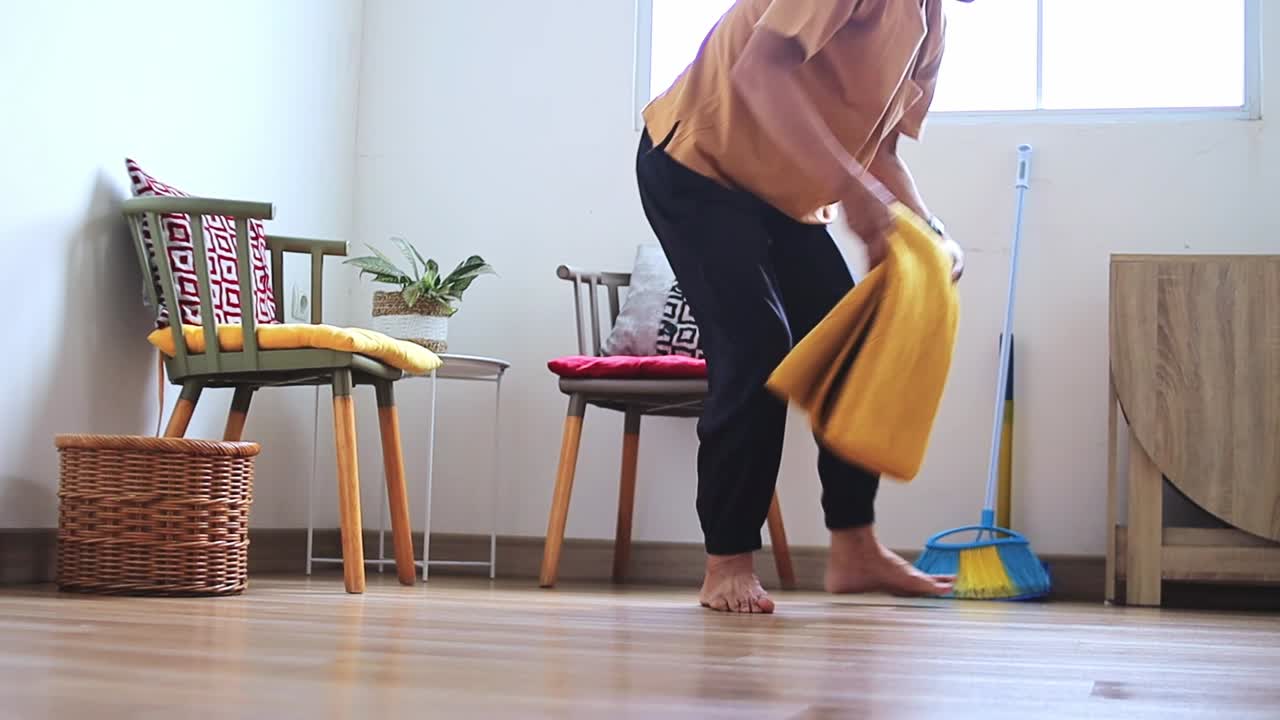 Elderly asian man folding yellow rug with care in bright comfortable home setting