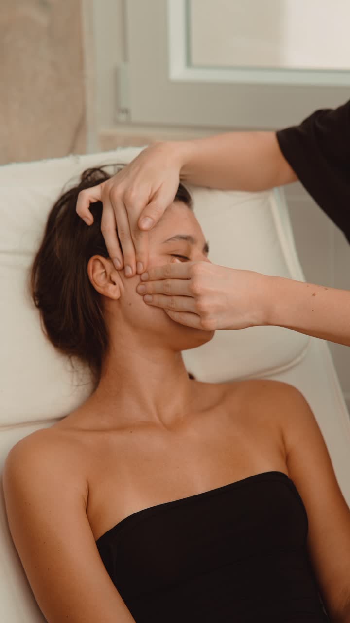 Mujer joven recibiendo un relajante masaje facial en un spa