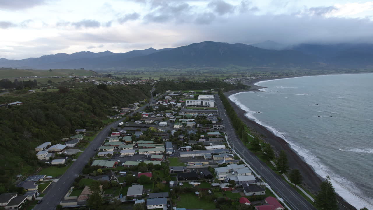 Drone flying backwards over the Kaikoura town, cloudy evening in New Zealand