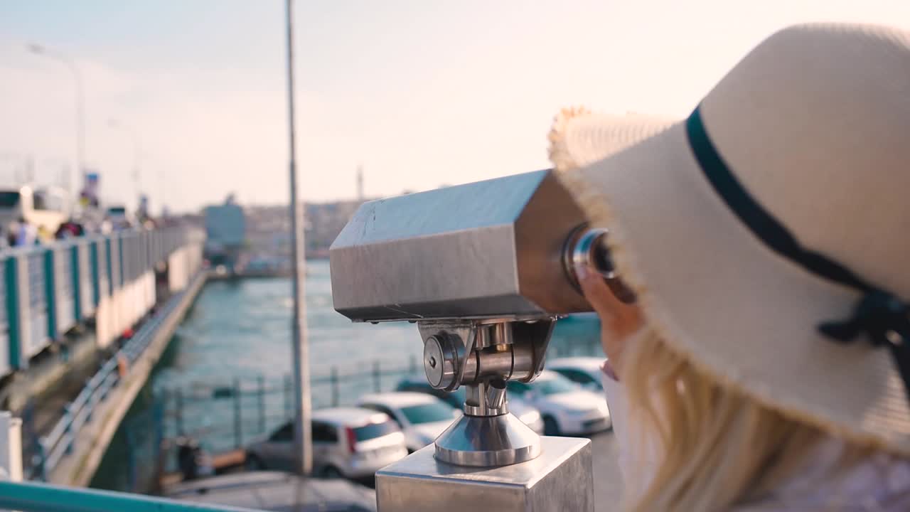 hermosa joven mira a través de binoculares turísticos con vistas a la torre de galata y al distrito de eminonu en estambul, turquía