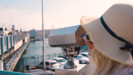 hermosa joven mira a través de binoculares turísticos con vistas a la torre de galata y al distrito de eminonu en estambul, turquía
