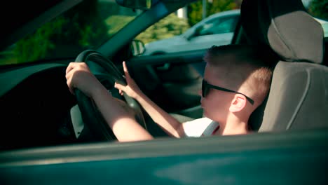 view from the side of a child playing in the vehicle interior turns steering wheel on the car