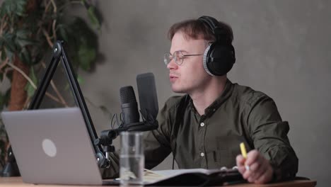 a male radio host or podcaster speaks into a microphone with headphones creates audio content in the studio or on the radio on the air