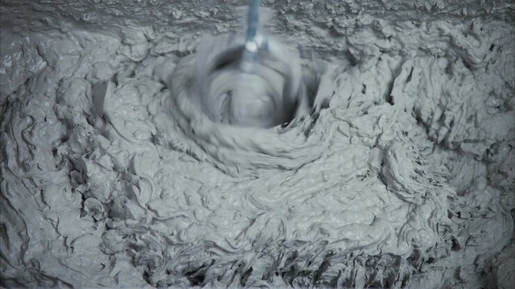 Electric Drill Mixing Thick Gray Mortar in Bucket