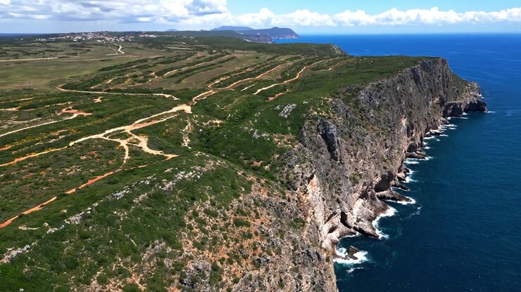 Scogliere costiere spettacolari e oceano blu profondo lungo la costa frastagliata vicino a Cabo Espichel, Portogallo. Paesaggio scenografico con sentieri tortuosi e viste mozzafiato sul mare, viste aeree.