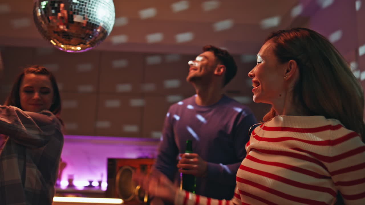 Friendly company dancing night gathering at home illuminated disco ball close up