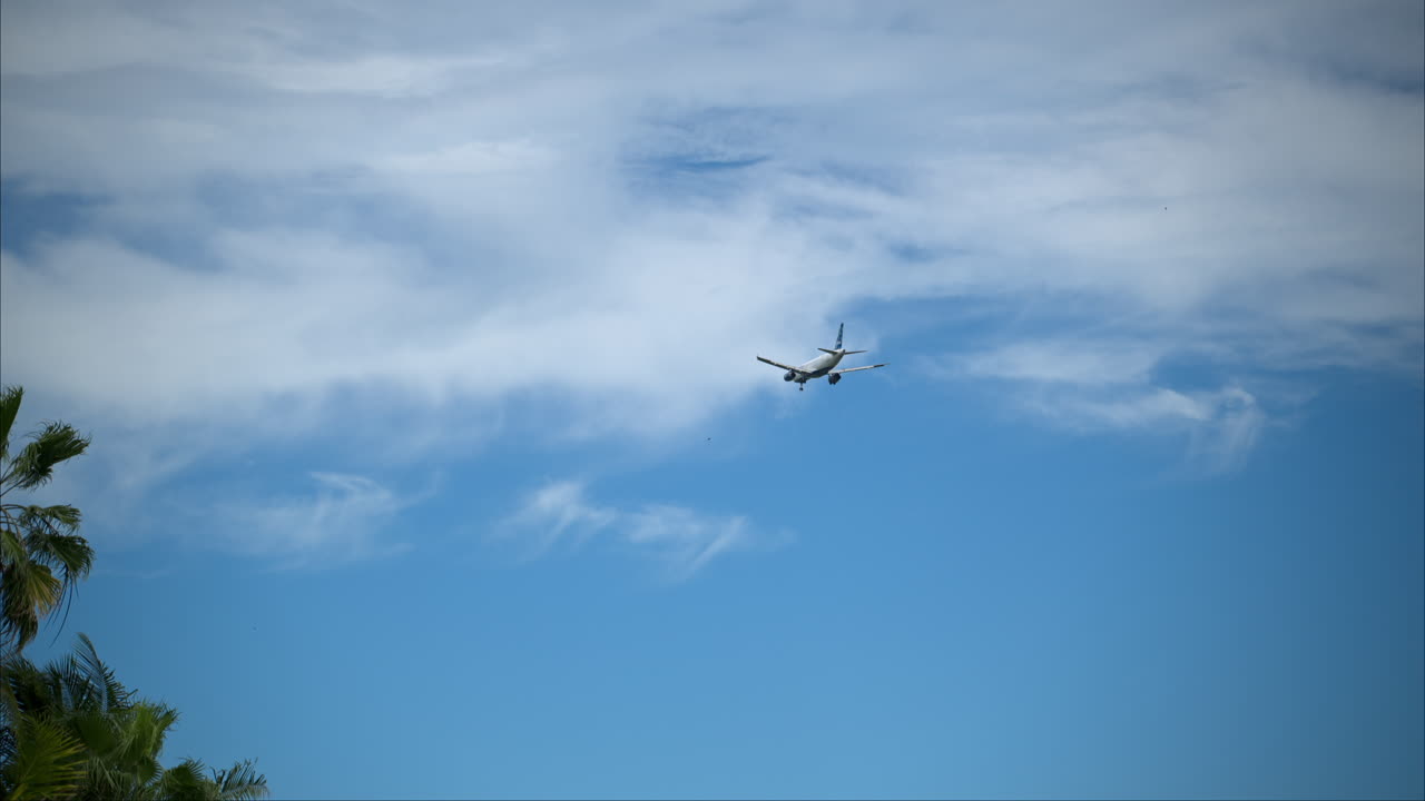 Ralenti d'un avion volant dans le ciel bleu avec des nuages, se préparant à atterrir à Cancún, Mexique